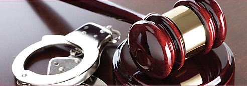 A gavel and handcuffs on a desk