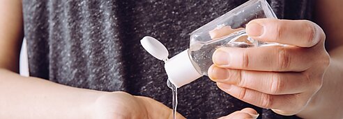 A person squeezing hand sanitizer into their hands