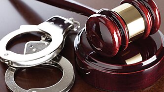 A gavel and handcuffs on a desk